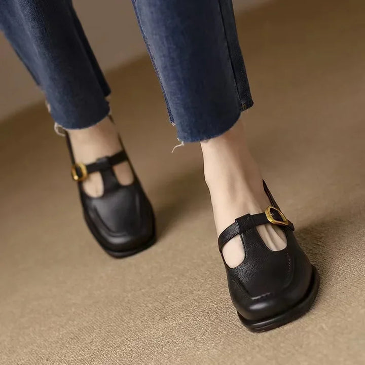 Black T-strap loafers with gold buckle and cutout toe opening