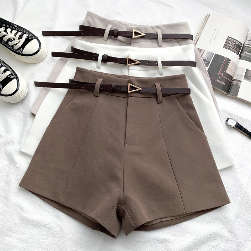 Taupe high-waist shorts with front crease, belt loops, and faux leather belt with gold buckle