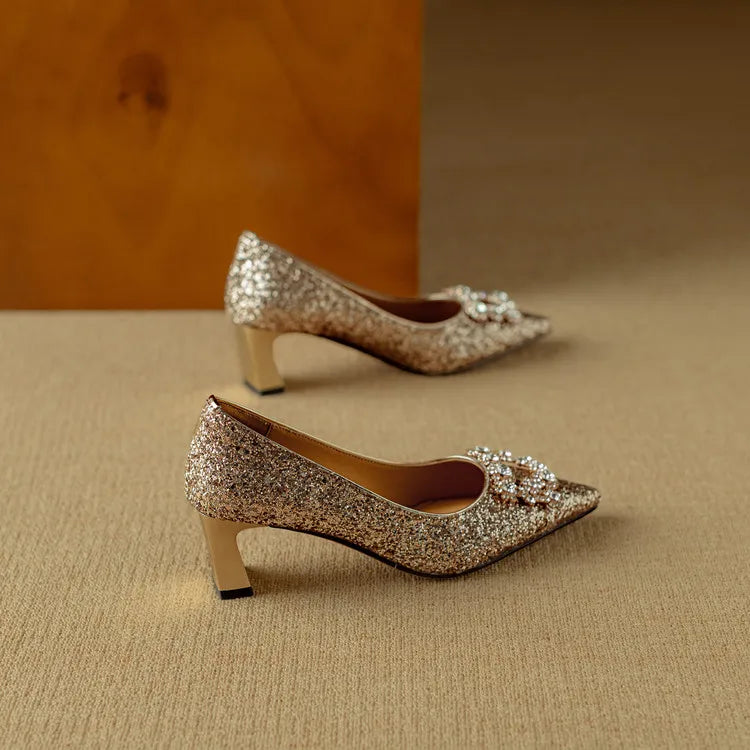 Gold-toned glitter pumps with pointed toe, jeweled bow, and stacked low block heels