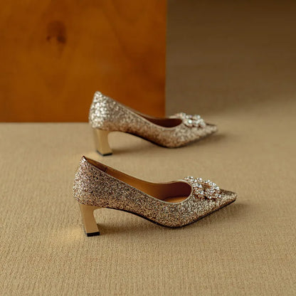 Gold-toned glitter pumps with pointed toe, jeweled bow, and stacked low block heels