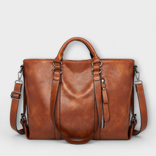 Large leather bag with top handles, side zippers, and crossbody straps in brown.
