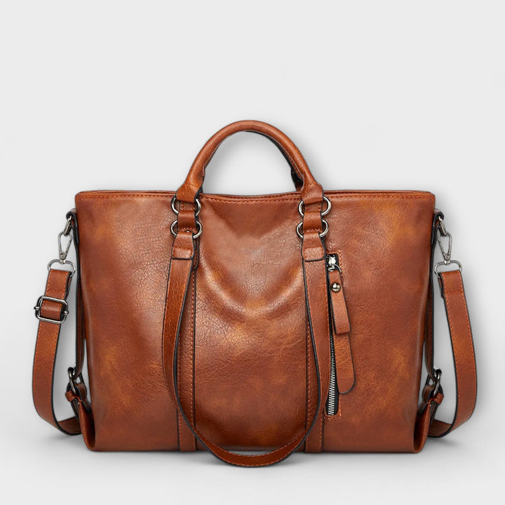 Large leather bag with top handles, side zippers, and crossbody straps in brown.
