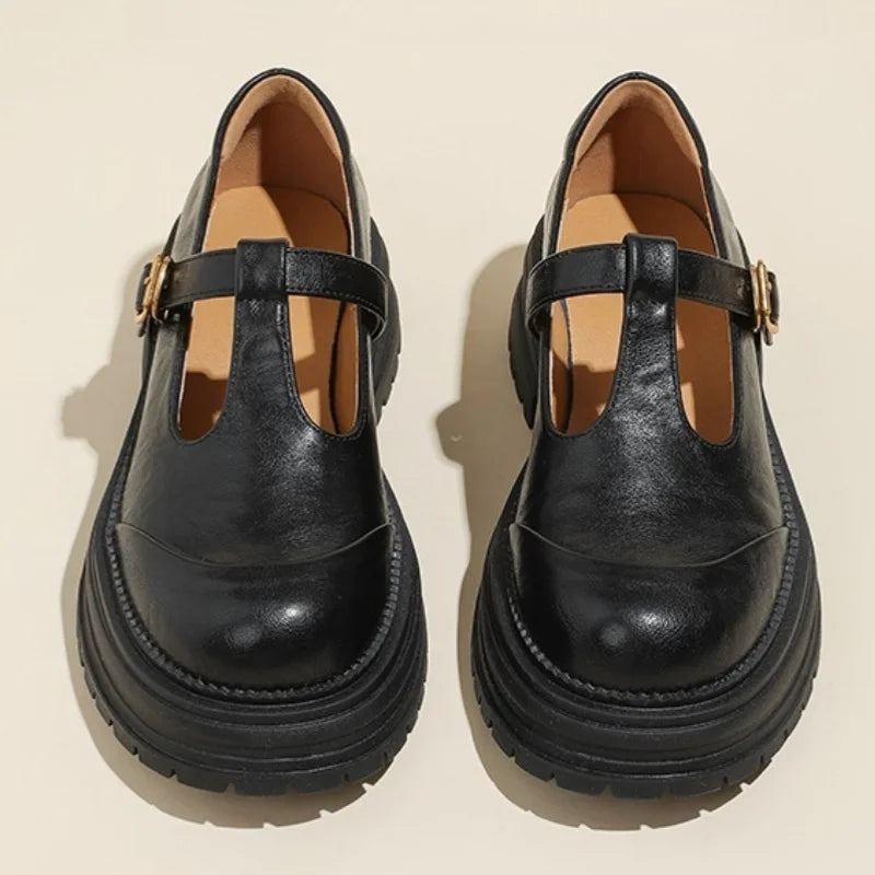 Black T-bar shoes with gold buckle strap and thick sole, front view