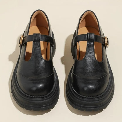 Black T-bar shoes with gold buckle strap and thick sole, front view