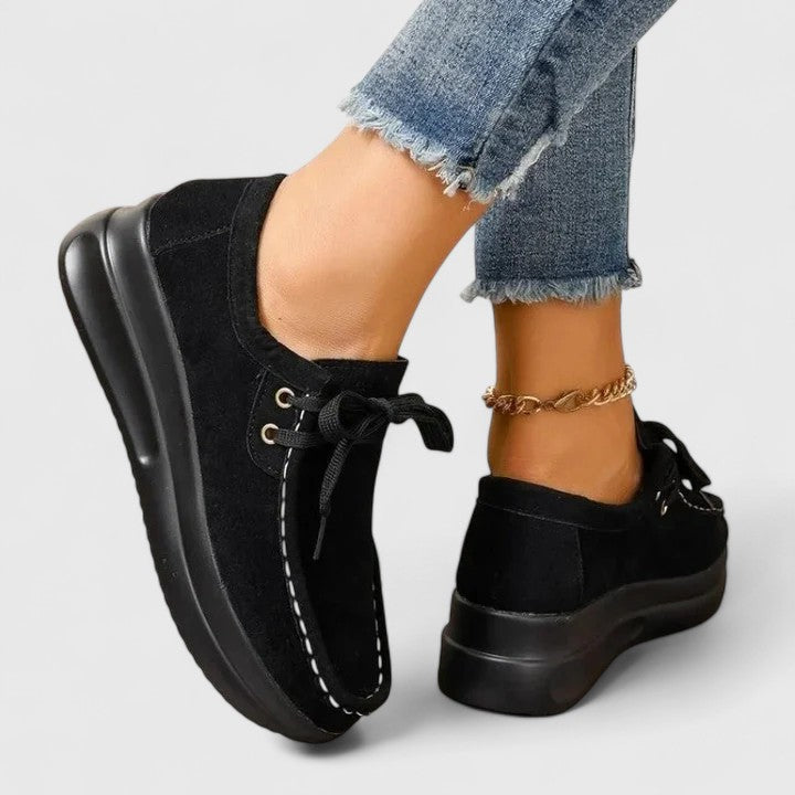 Black lace-up orthopedic shoe with suede upper and thick black sole.
