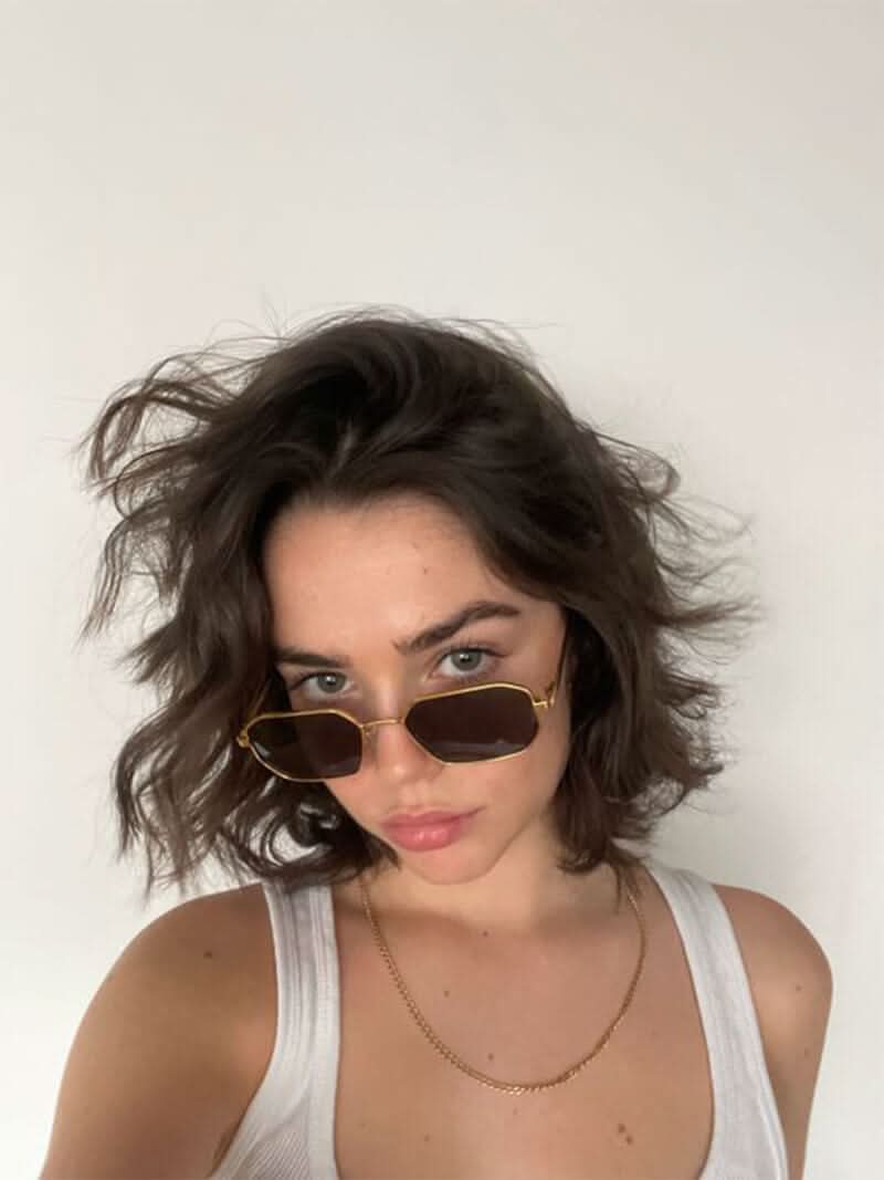 Gold sunglasses with brown tinted lenses and slim temples on model