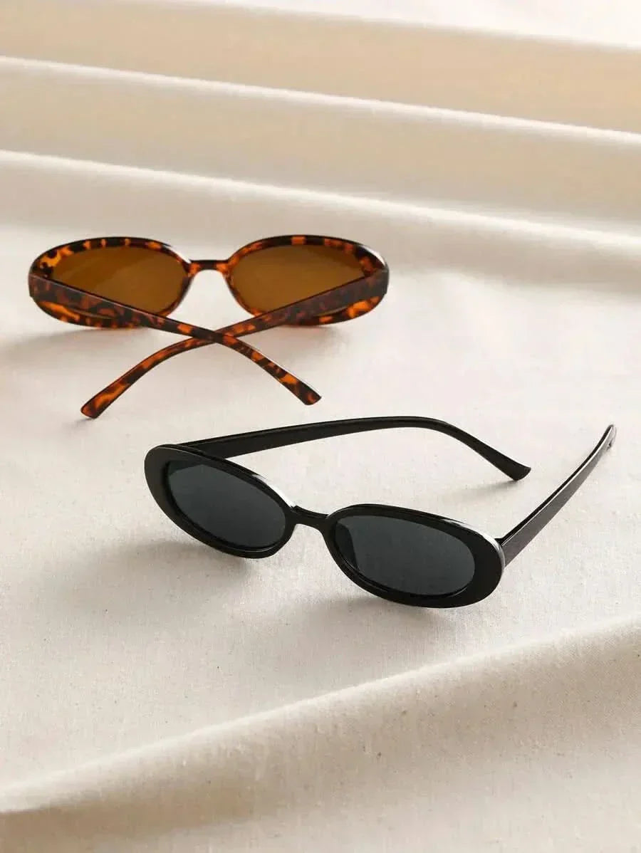 Tortoiseshell and black oval sunglasses on a surface with dark lenses