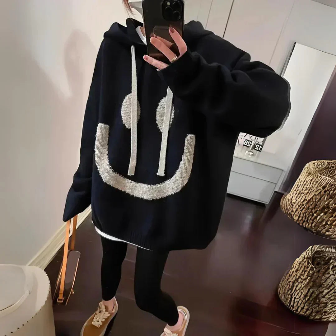 Black oversized hoodie with large white smiley graphic, hood, and ribbed cuffs