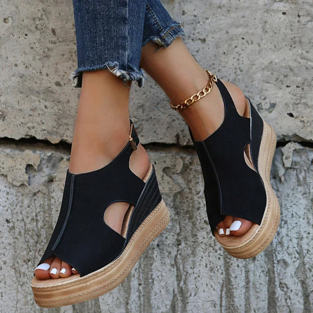 Black wedge sandals with open toe, ankle strap, and textured platform sole