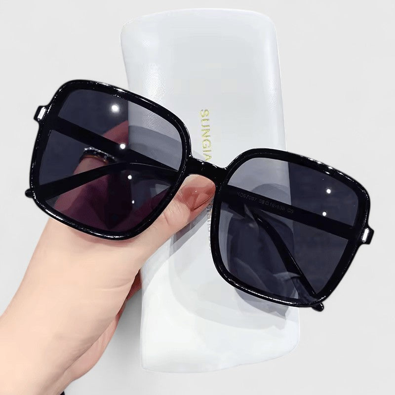 Elegant sunglasses with black frame and dark tinted lenses, oversized square style.