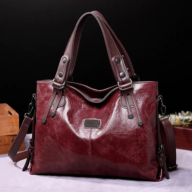 Wine red soft leather tote bag with double handles, side straps, and front logo patch