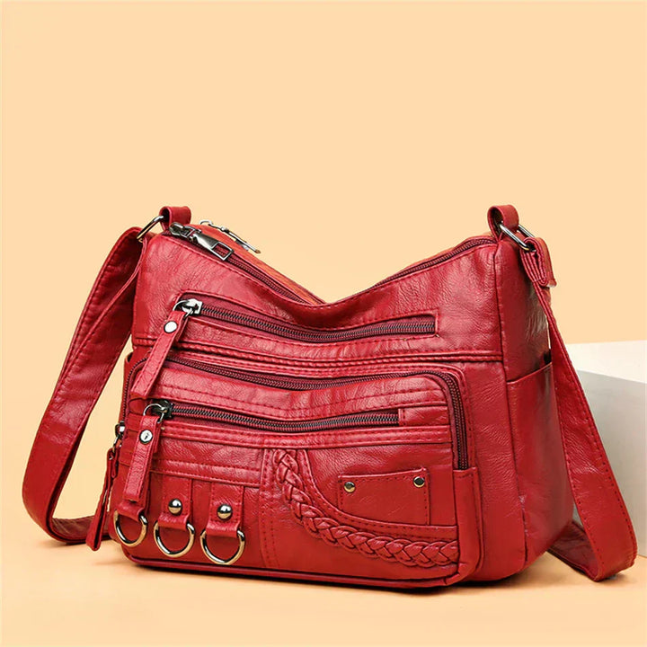 Red multi-layer crossbody bag with zip compartments, braided front pocket, and metal ring pulls