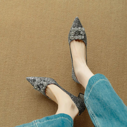 Silver glitter pointed-toe pumps with slim heel and bow-like gem detail at the vamp