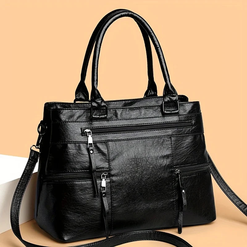 Black leather women’s tote bag with double handles, front zip pocket and adjustable crossbody strap