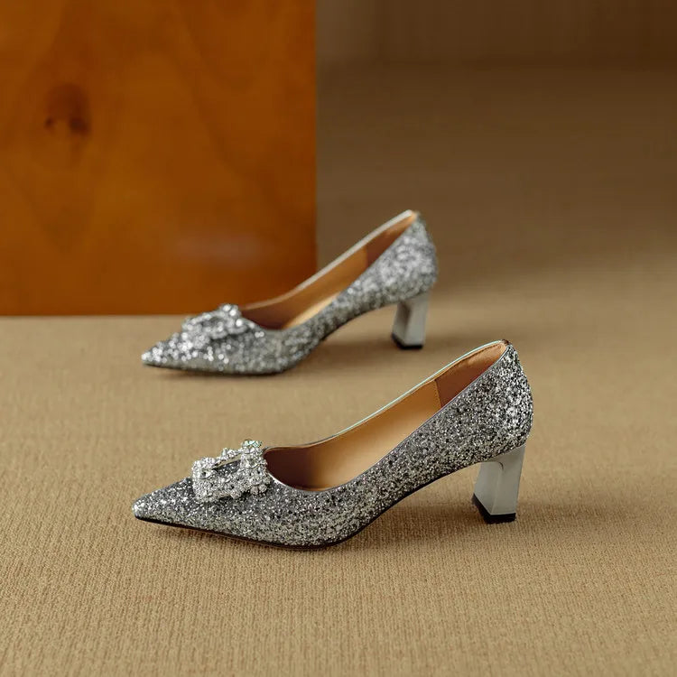 Silver glitter pointed-toe pump with bow-like rhinestone embellishment and mid heel