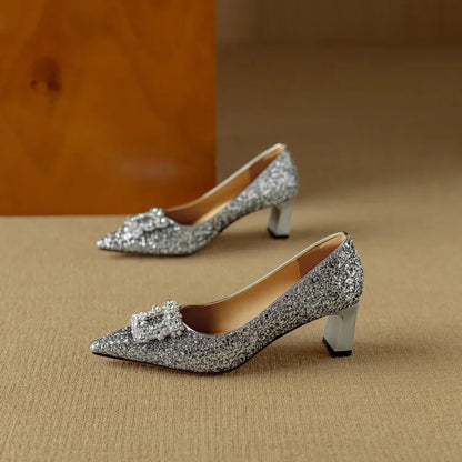 Silver glitter pointed-toe pump with bow-like rhinestone embellishment and mid heel