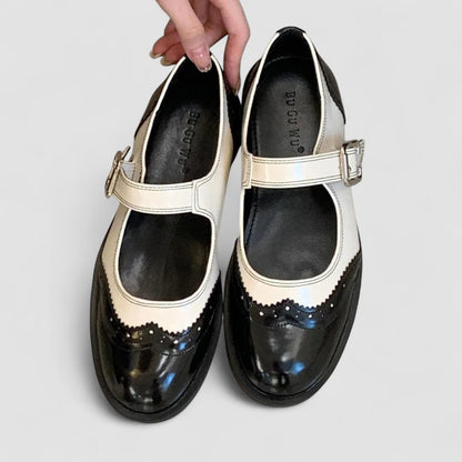Black Mary Jane shoes with white trim, buckle strap, and polished finish
