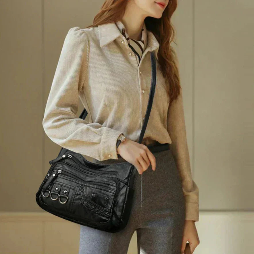 Black multi-layer crossbody bag on a model, with layered zip compartments and straps