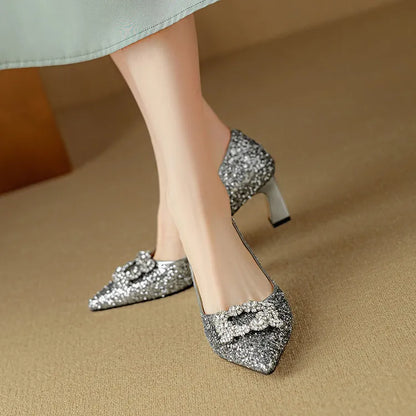 Silver-toned glitter pumps, close side view with pointed toe, jeweled bow, and block heel