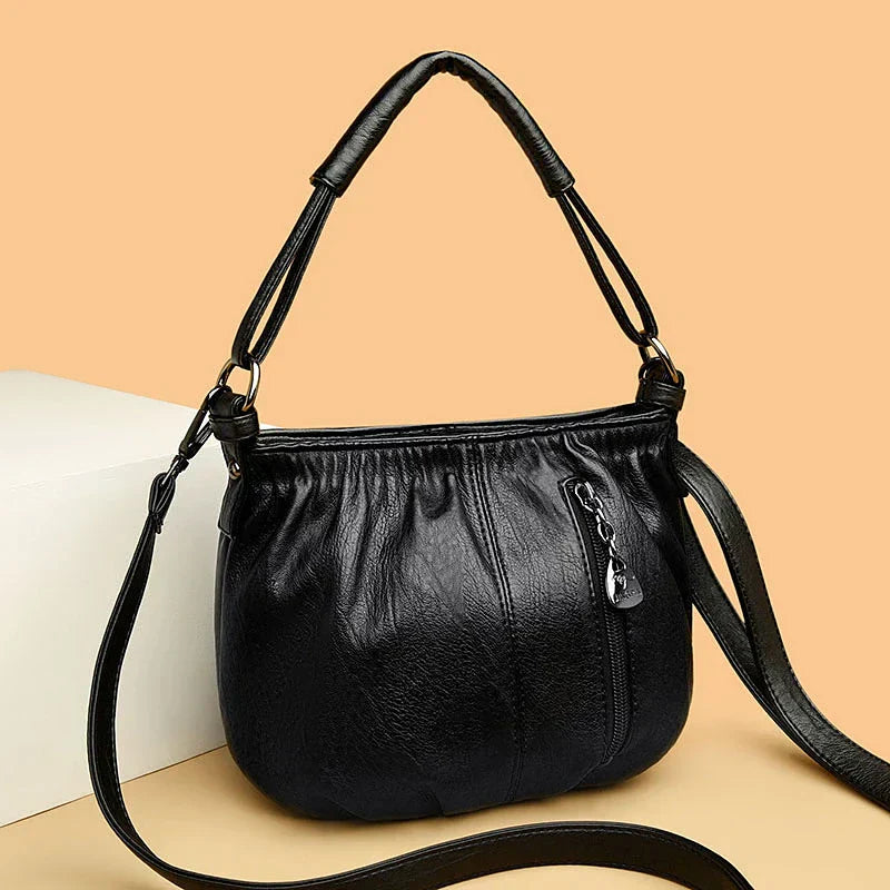 Black multi-layer handbag with gathered front, top handles, and detachable shoulder strap