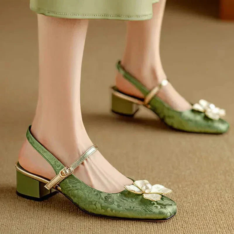 Green elegant pumps with ankle strap, gold trim, and white flower embellishment