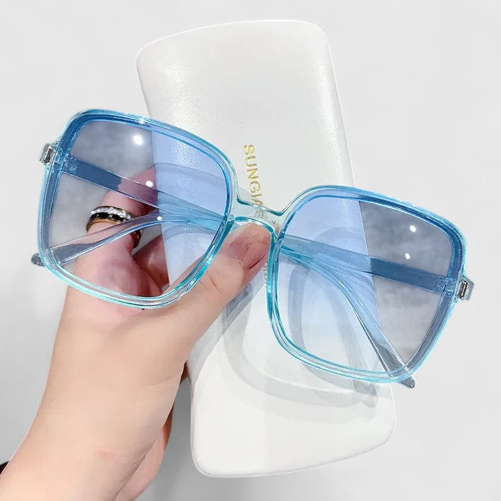 Elegant sunglasses with light blue frame and blue tinted lenses, oversized square style.