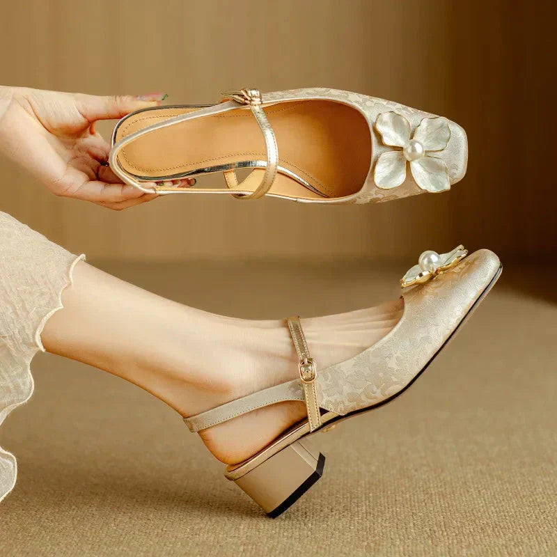 Beige slingback pumps with floral appliqué, ankle strap, low block heel in hand