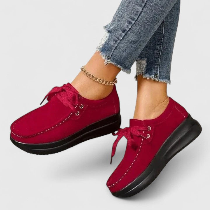 Red lace-up orthopedic shoe with suede upper and thick black sole.
