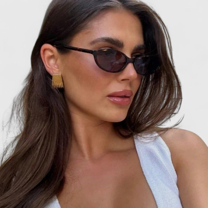 Sunglasses on model with black frames and dark lenses, rounded cat-eye style