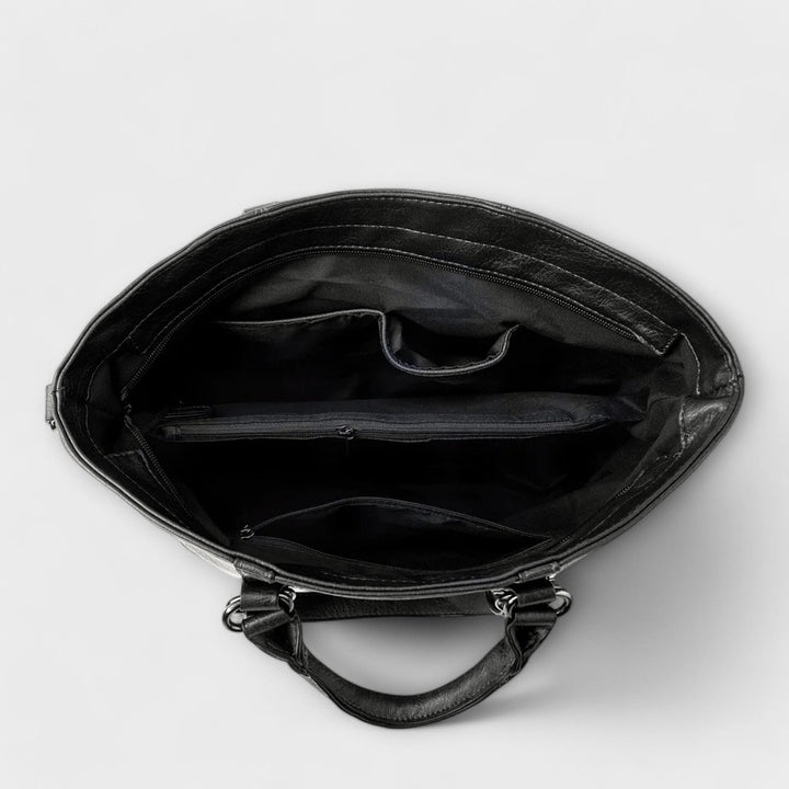 Black leather bag interior view with main compartment and zip pocket lining.