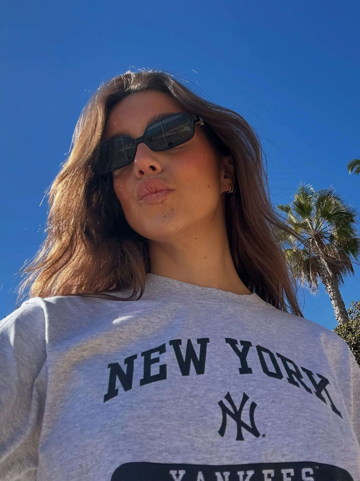 Dark square sunglasses with black lenses on a person outdoors