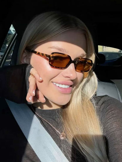 Tortoise square sunglasses with amber-brown lenses on a smiling person