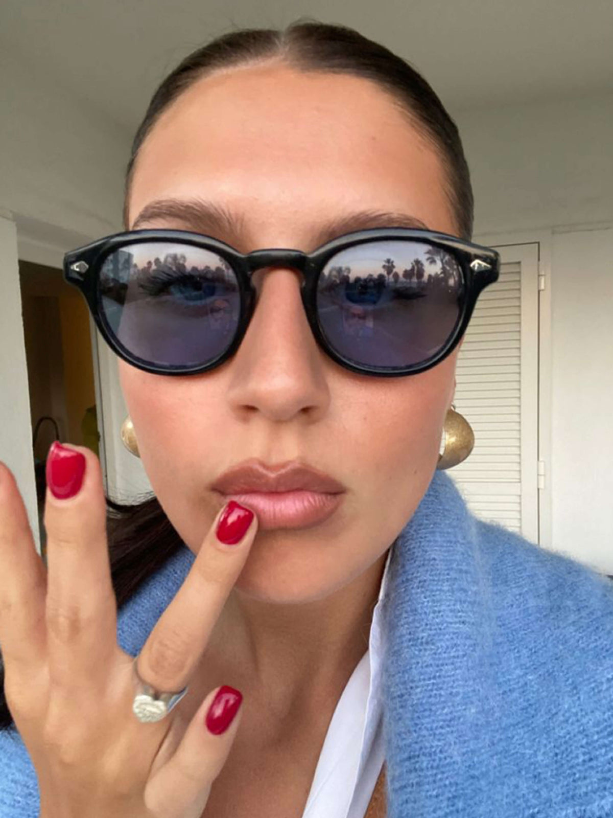 Black round sunglasses with dark mirrored lenses and small triangular accents