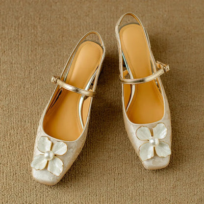 Beige elegant pumps pair with ankle strap, gold trim, and white flower ornament