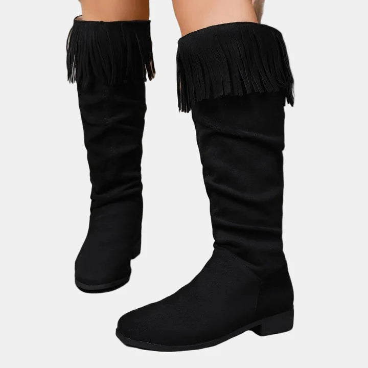 Black knee-high tassel boots with ruched shaft and block heel.