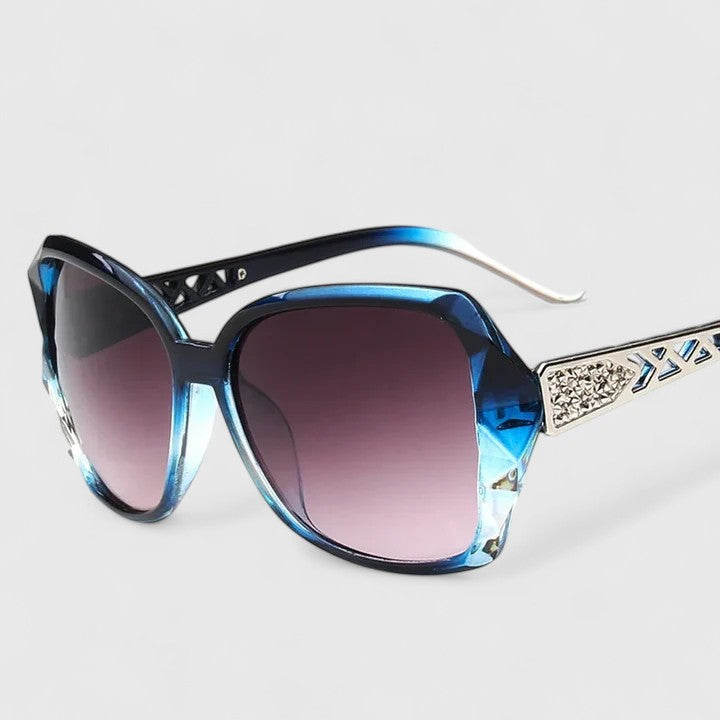 Sophisticated sunglasses, blue-tinted frame with purple gradient lenses and rhinestone temple bar.