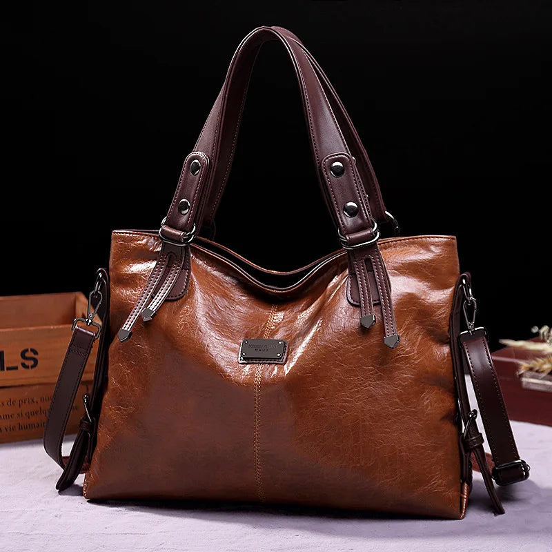 Brown soft leather tote bag with double handles, side straps, and front logo patch