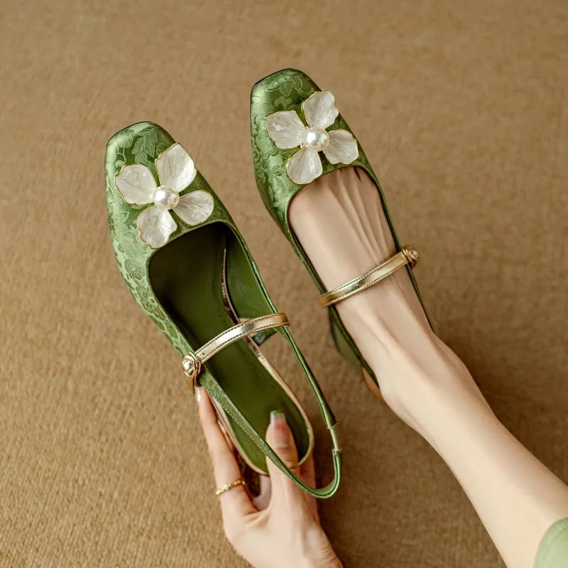 Green slingback pumps with floral appliqué, ankle strap, low block heel on hand