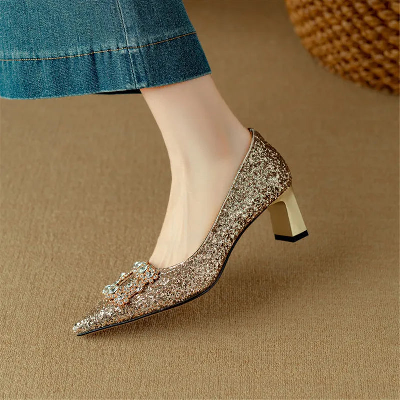 Gold-toned glitter pumps with pointed toe and jeweled bow, shown from side