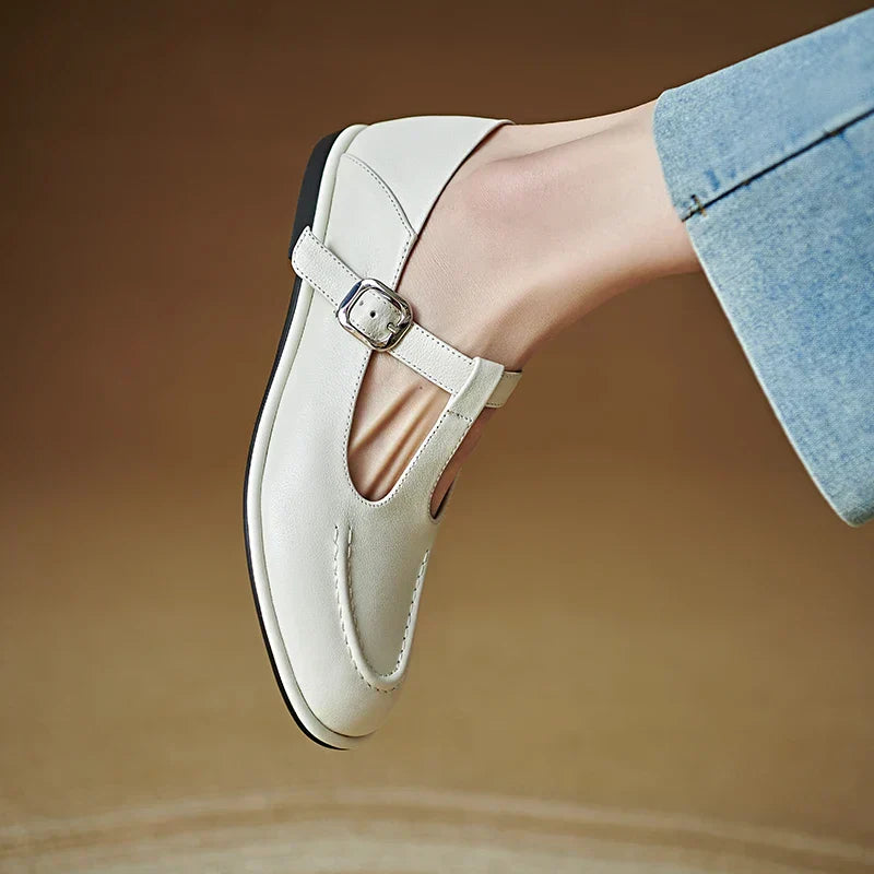 Light beige low-heeled Mary Jane pumps, side view with T-strap and buckle, rounded toe.