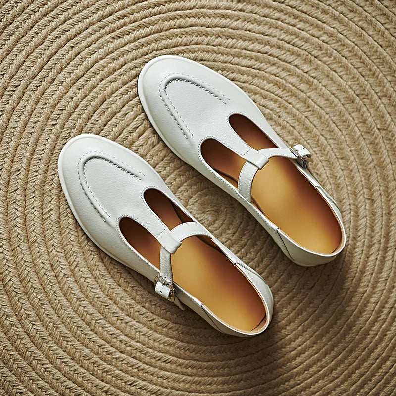 Pair of light beige low-heeled Mary Jane pumps with T-strap and buckle, rounded toe.
