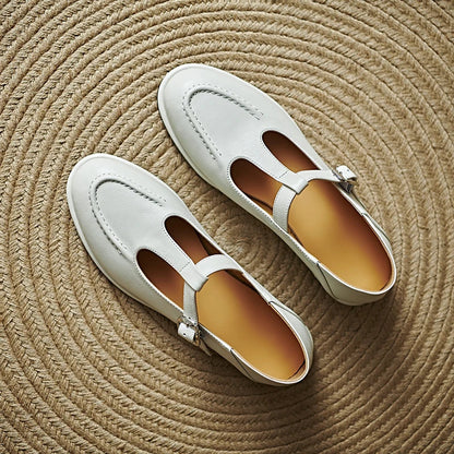 Pair of light beige low-heeled Mary Jane pumps with T-strap and buckle, rounded toe.