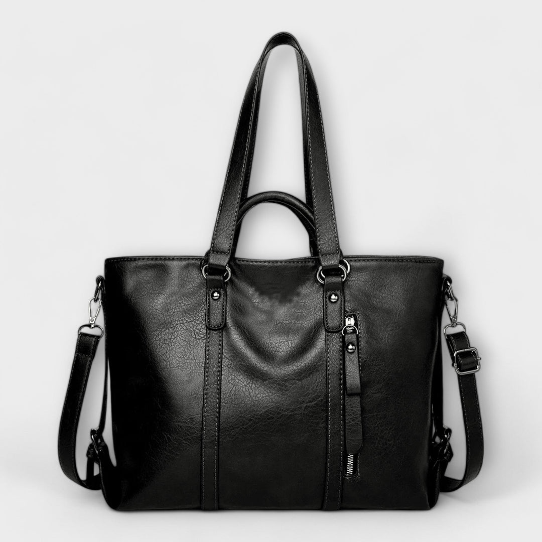 Large black leather bag with top handles, side zippers, and crossbody strap.