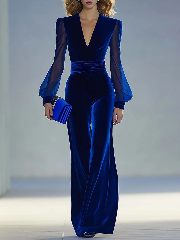 Blue suede V-neck jumpsuit with long fitted sleeves and pleated waist seams