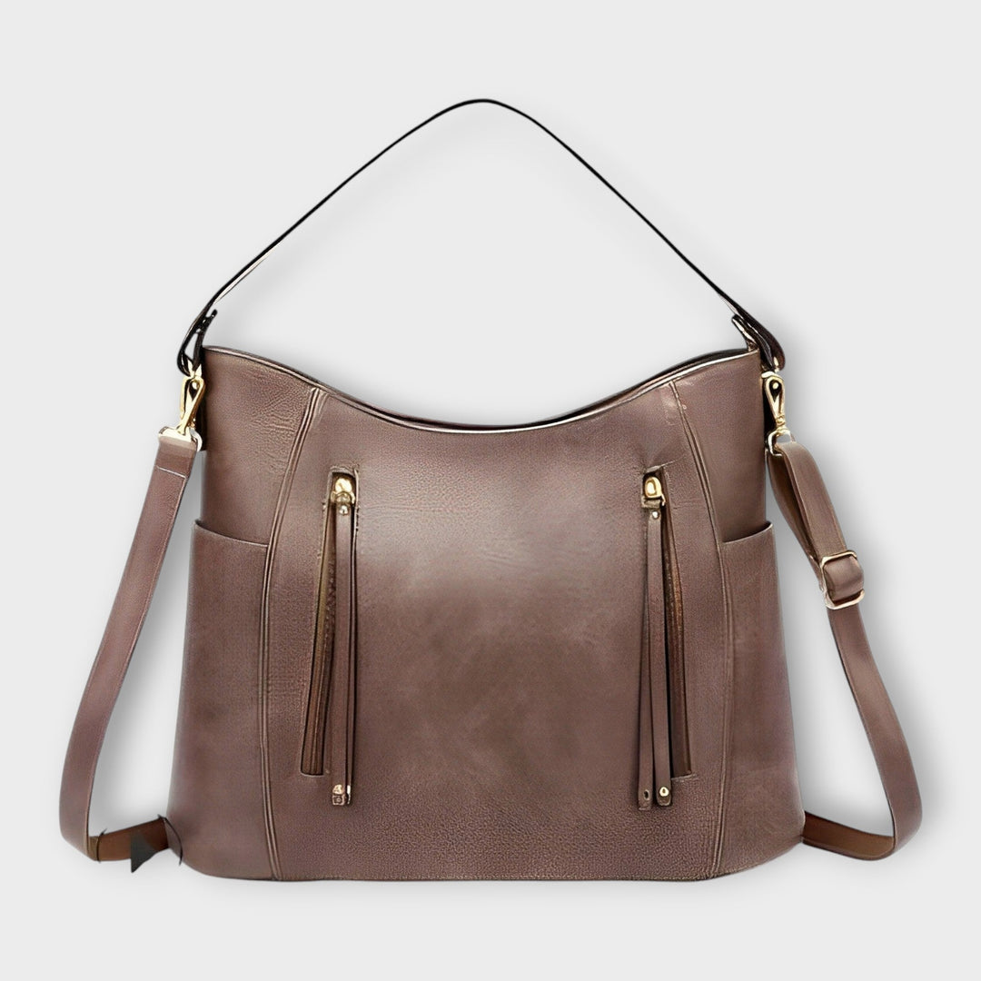 Taupe leather hobo handbag with zip front, tassel details, and shoulder straps.