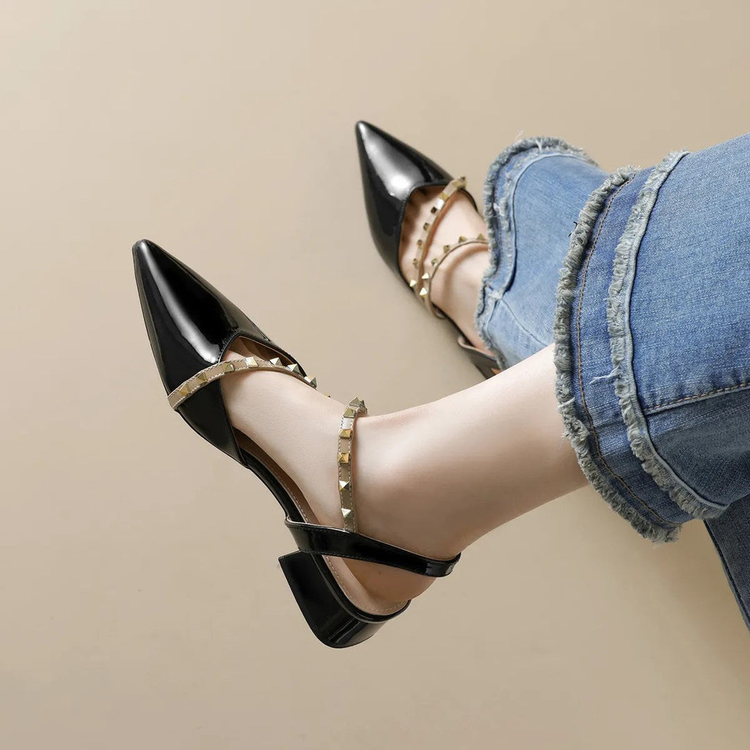 Black orthopedic heels with pointed toe, strappy upper, and gold-tone stud trim, side view