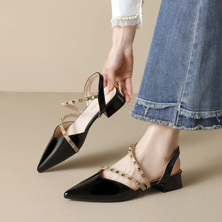 Black orthopedic heels with pointed toe, ankle strap, and gold-tone stud trim, block heel
