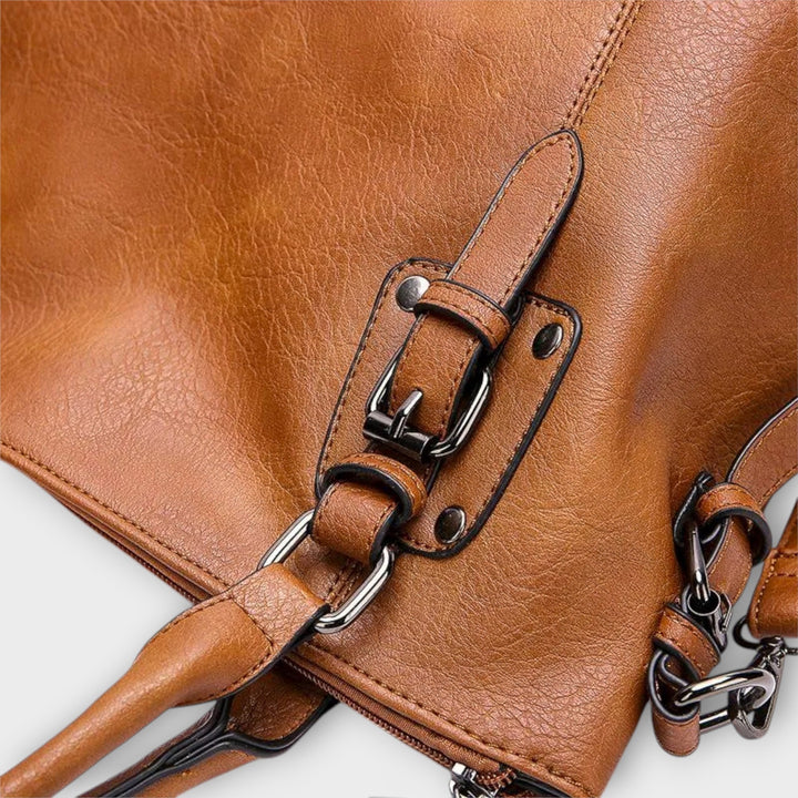 Brown shoulder bag detail: front buckle strap and chain crossbody attachment