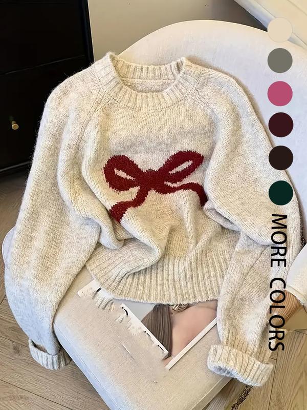 Cream knit sweater with ribbed crew neck, cuffs, and large red bow intarsia