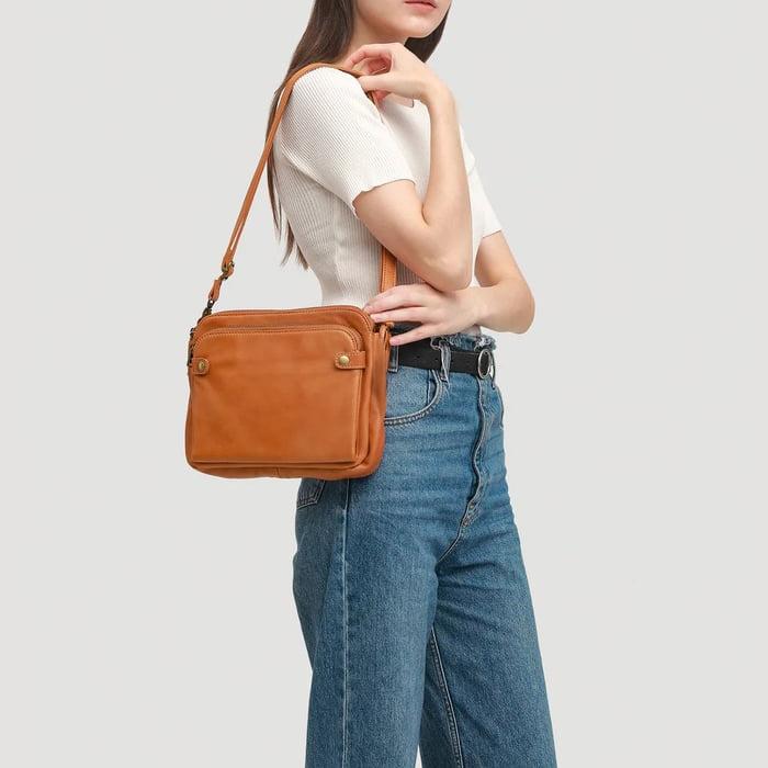 Orange-brown crossbody bag worn over the shoulder with zip front pockets